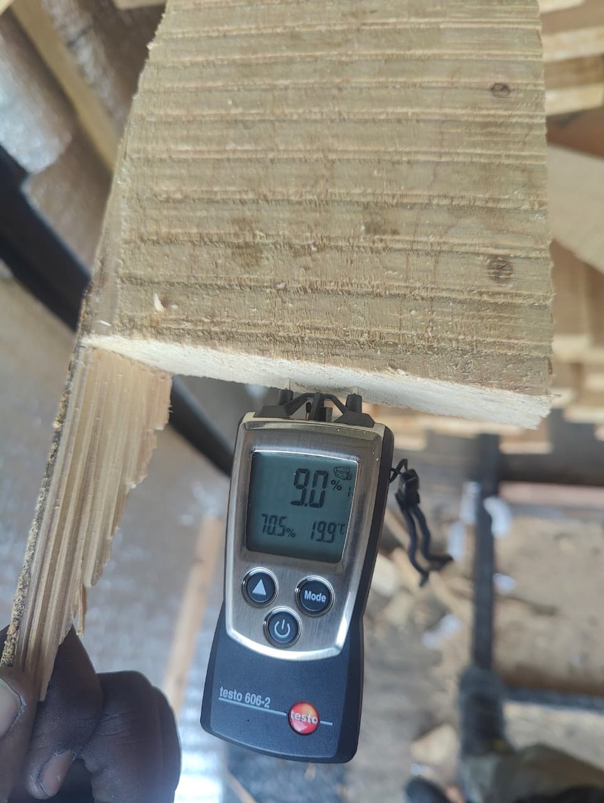 A moisture meter held against a cypress board in the TimberStone workshop, reading 9.0 percent