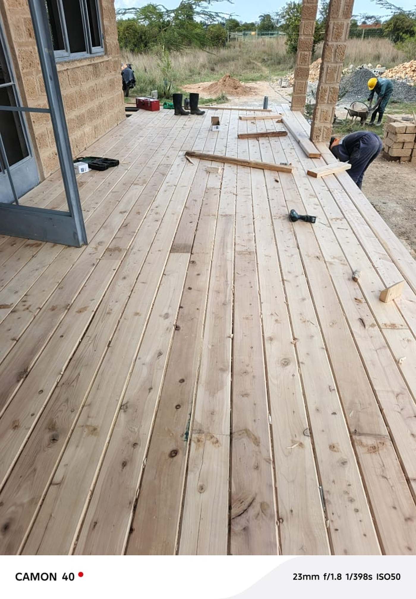 A timber deck being laid outside a stone house near Nanyuki, boards fixed and spaced