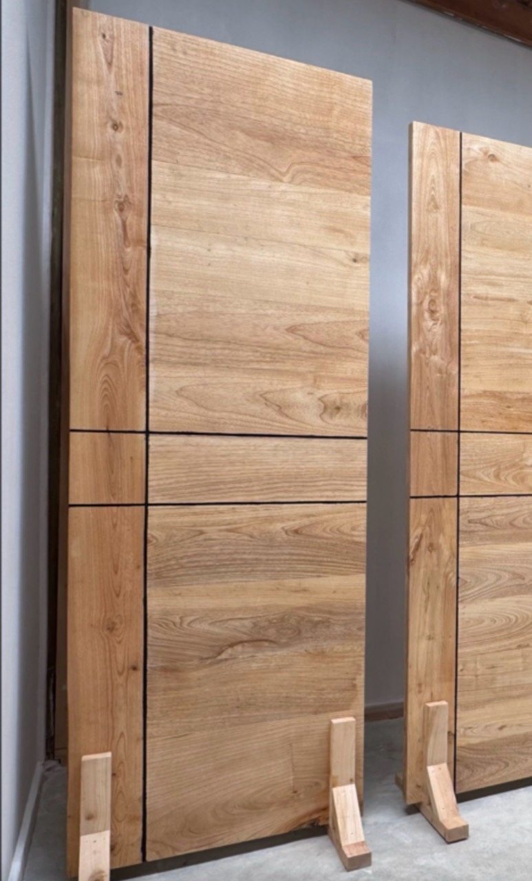 Two unfinished solid timber door panels with simple horizontal detailing, standing in the TimberStone workshop.