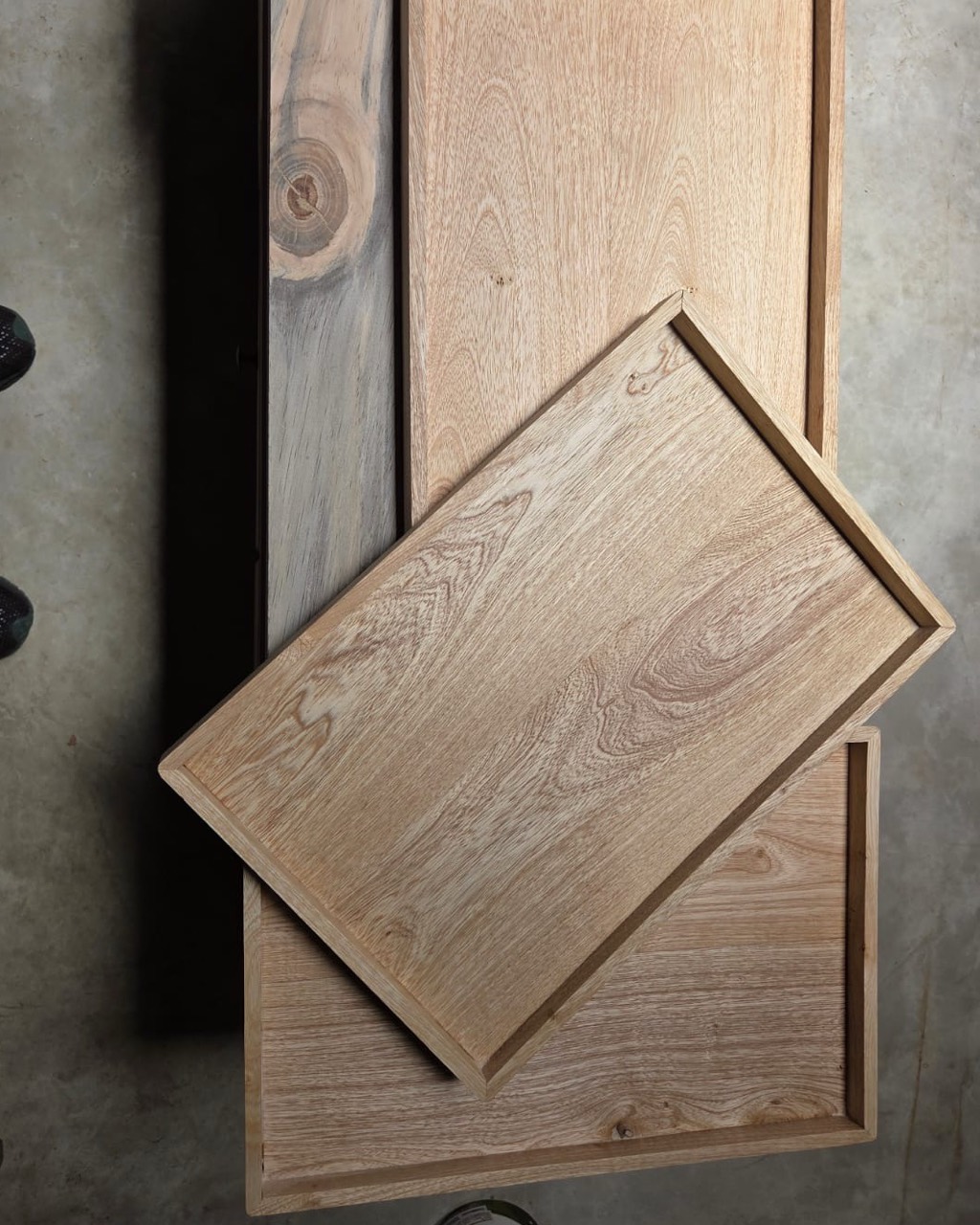 Three solid timber serving trays with raised edges, stacked in the TimberStone workshop.