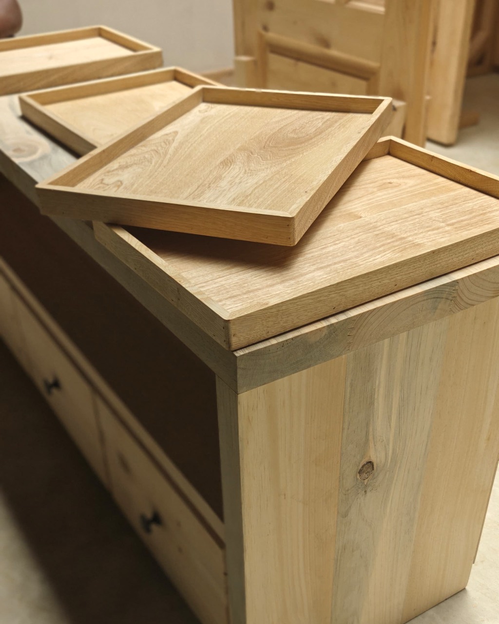 Solid timber serving trays laid on a workbench beside other workshop joinery.