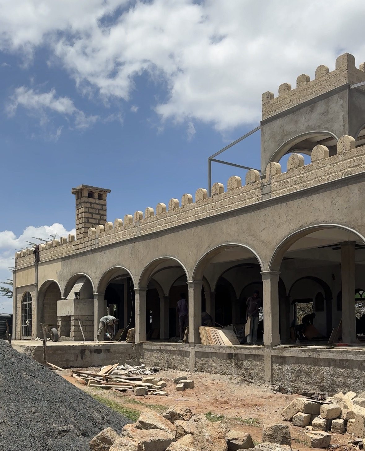 The arcade of the Lolldaiga pool house with its crenellated stone parapet and chimney while finishing work continues in October 2026.