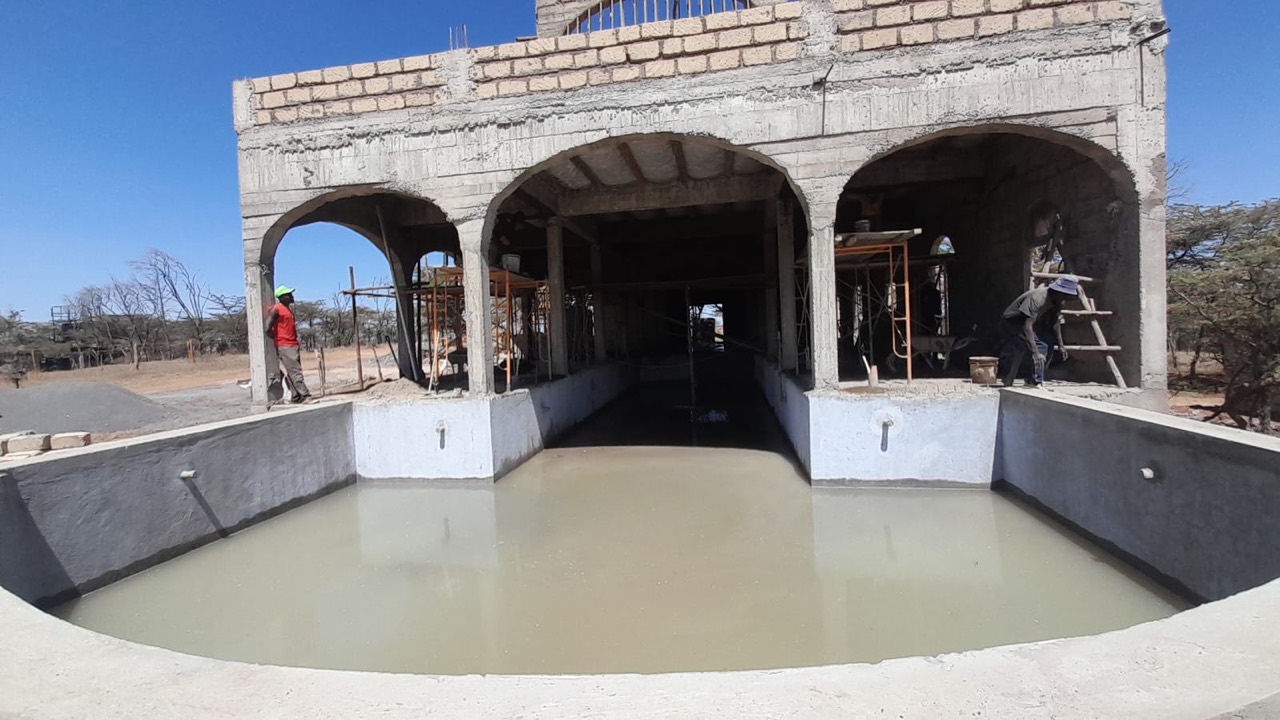 The pool shell holding water below the arched pool house under construction at Lolldaiga Hills.