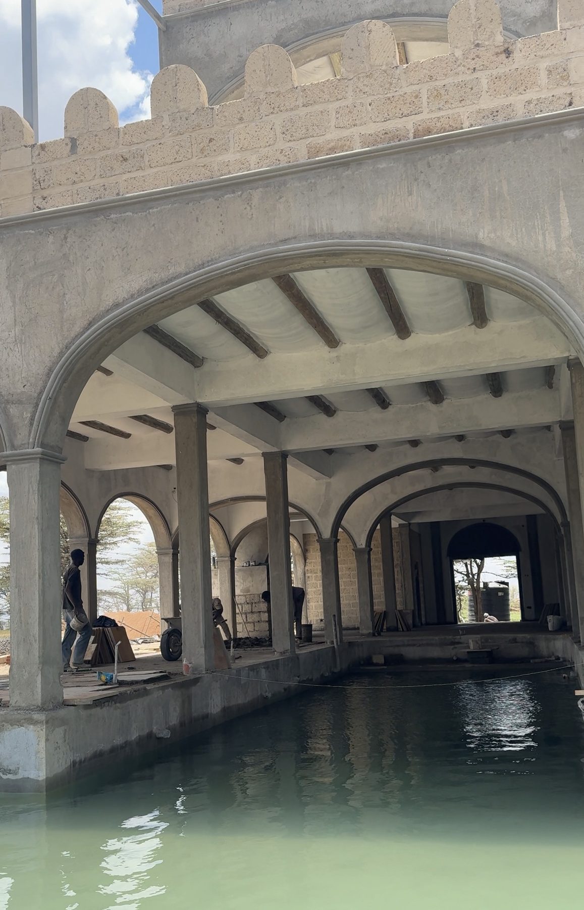 The completed, water-filled pool running beneath the arched pool house at Lolldaiga Hills in October 2026, with fit-out work continuing.