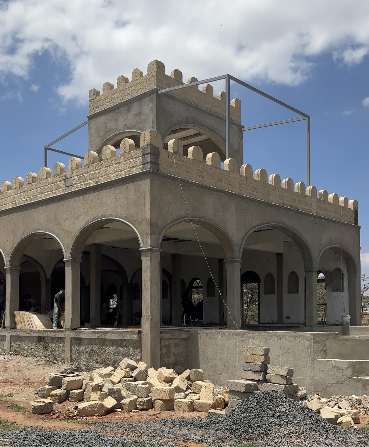 The corner tower and arches of the Lolldaiga pool house in October 2026, with a steel frame above the tower roof.